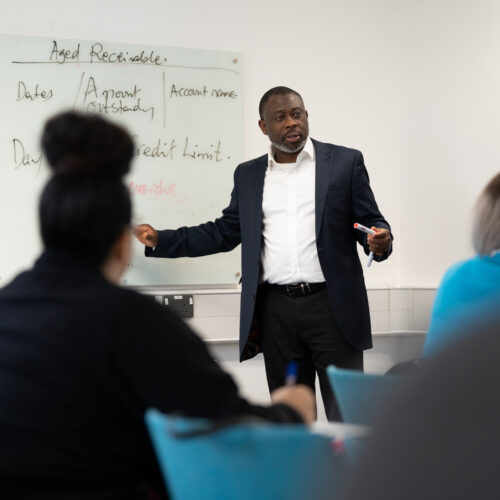 Accounting lecturer in front of a class at a whiterboard delivering a workshop