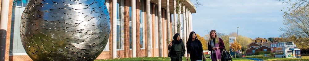 students walking past newman university globe