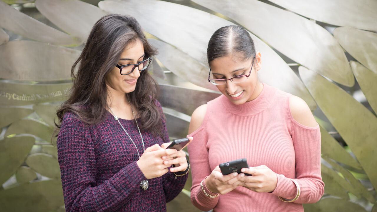 Two students looking at their mobile phones