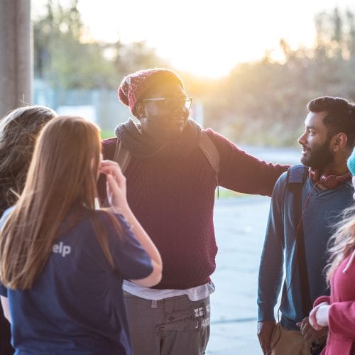 students in the entrance of the atrium with the sun behind them
