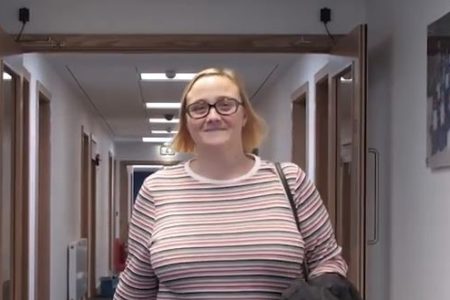 student marilyn walking down the corridor smiling at camera