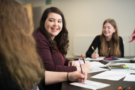 student shannen writing smiling at friend