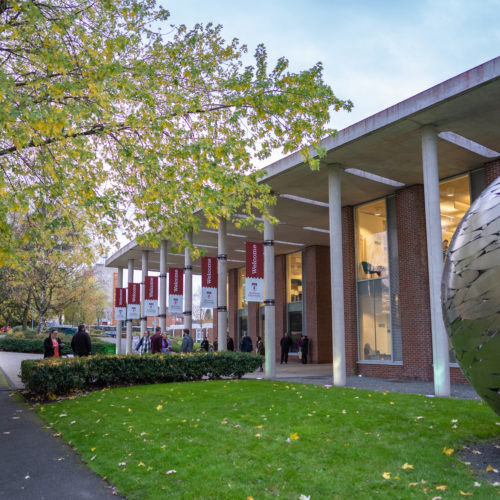 Newman front of campus with welcome flags