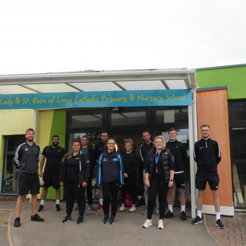 PGCE PE students standing outside a local primary school