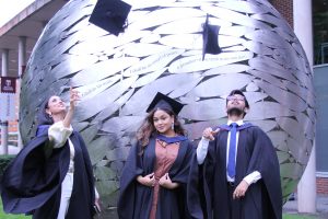 graduates throwing hats by the globe