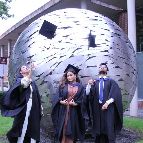 graduates throwing hats by the globe