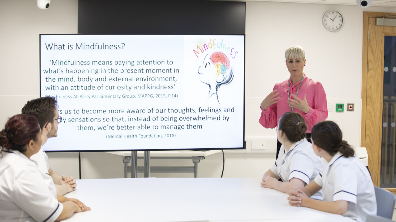 Lecturer using presentation screen to discuss mindfulness with nursing students