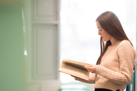 Student standing, researching new courses in Birmingham Newman University library