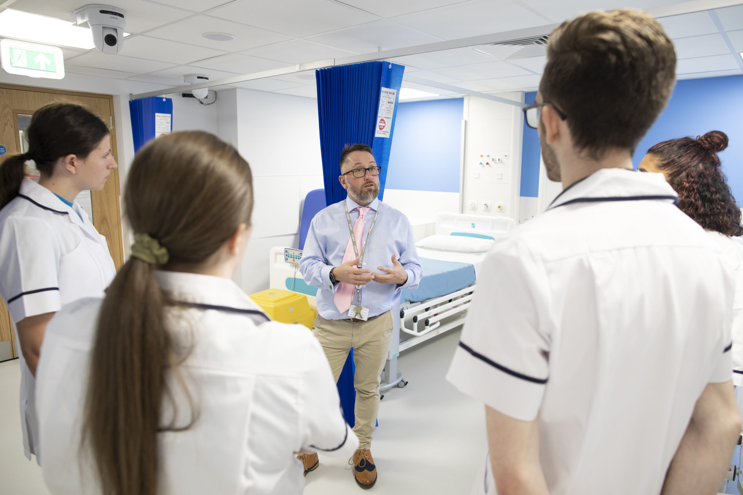 Lecturer talking to group of nursing students on university skills lab ward