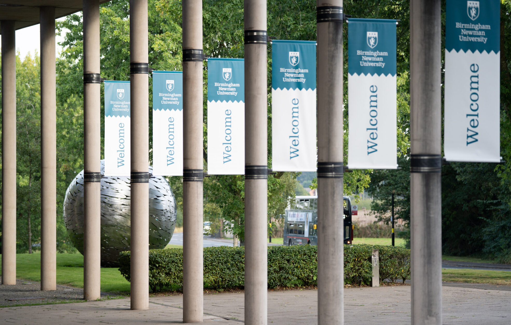 Welcome banners on pillars hanging outside Birmingham Newman University's campus