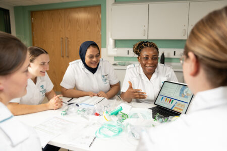 Group of student nurses are looking at and discussing medical equipment and a presentation.