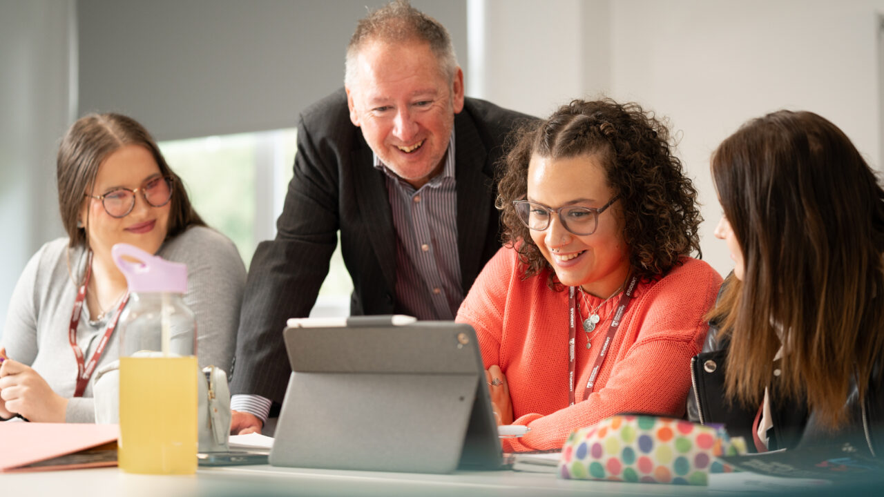 Lecturer talking to students gathered around a computer