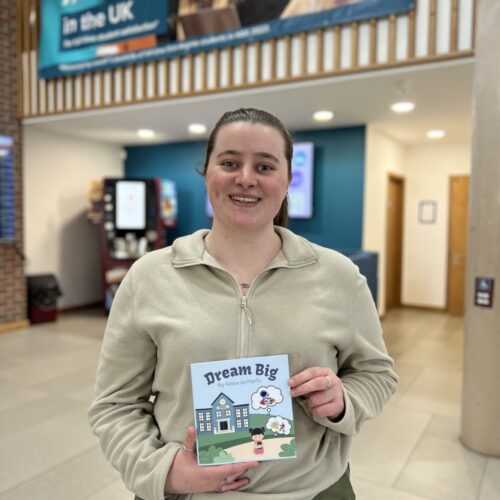 An image of Applied Humanities student, Adele Botterill holding her published book on Amazon called 'Dream Big'