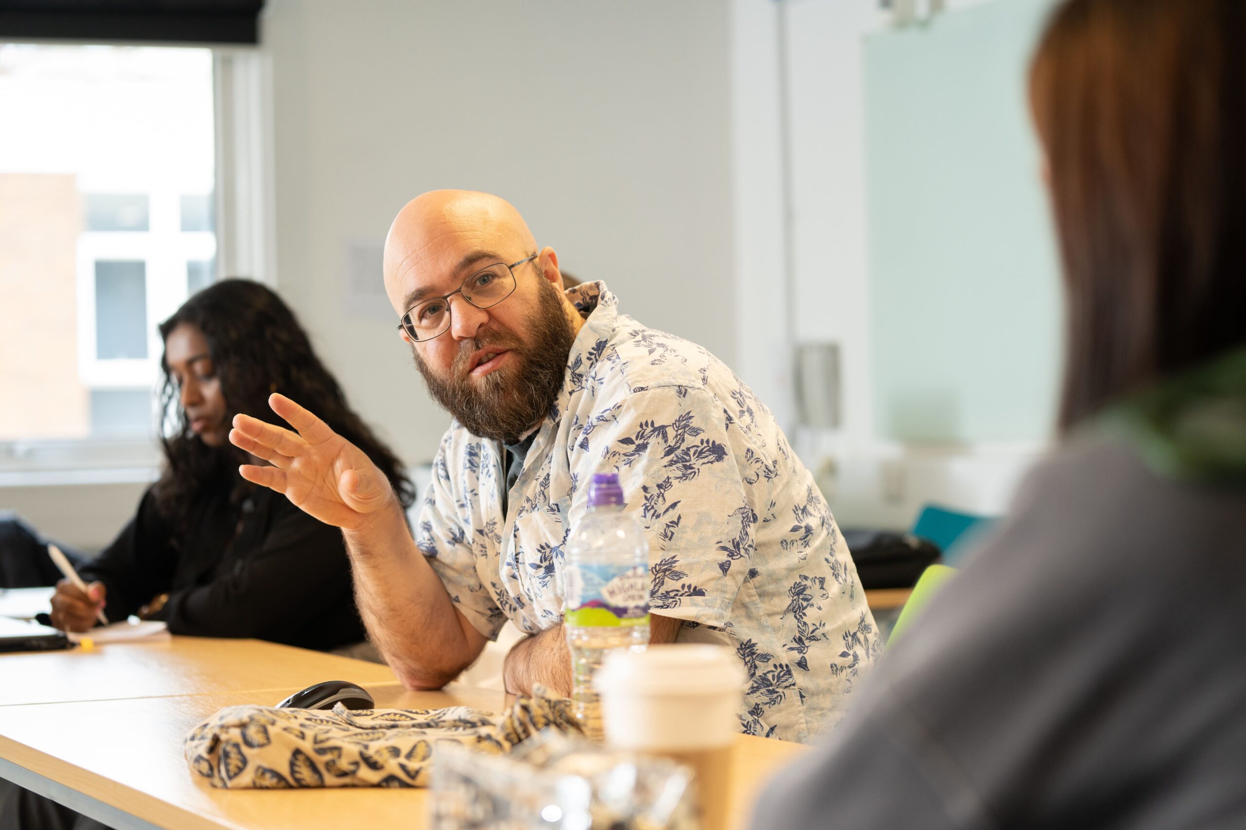 Lecturer sitting down talking to students in classroom