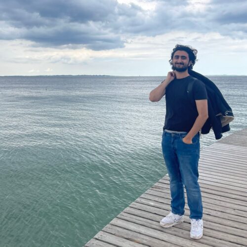 Zayb Nazir - Newman student standing near water in Denmark