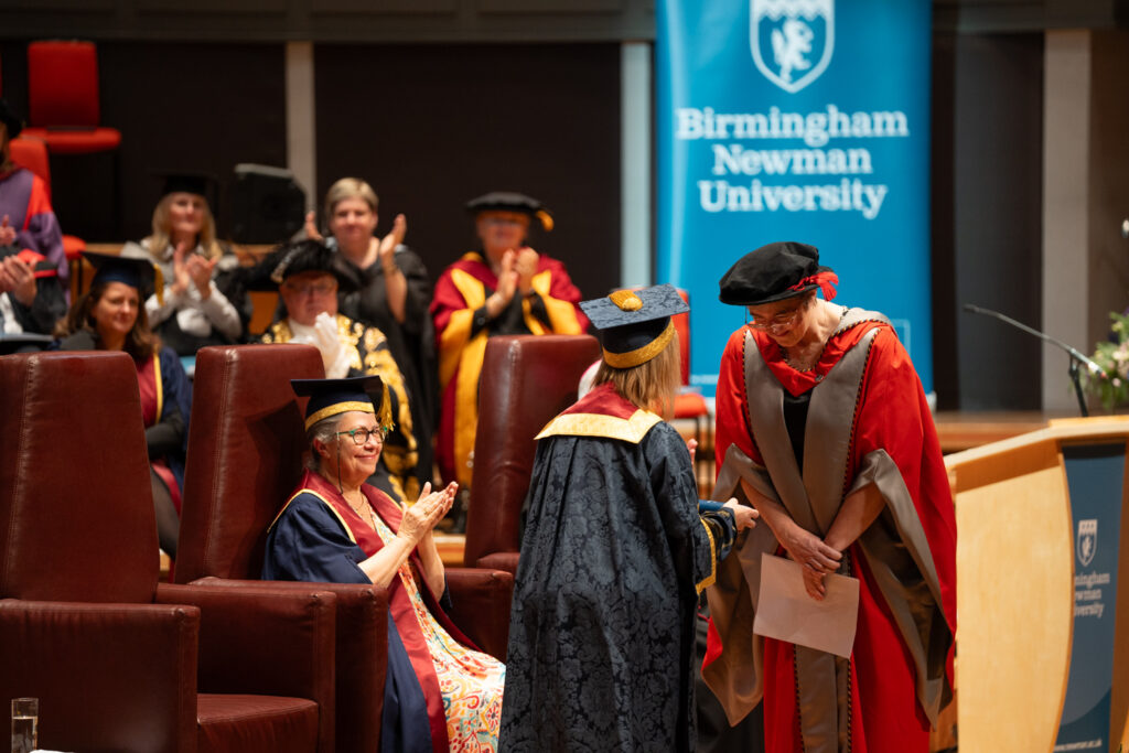 Dr Dawn Casserly receiving honorary degree from VC on stage