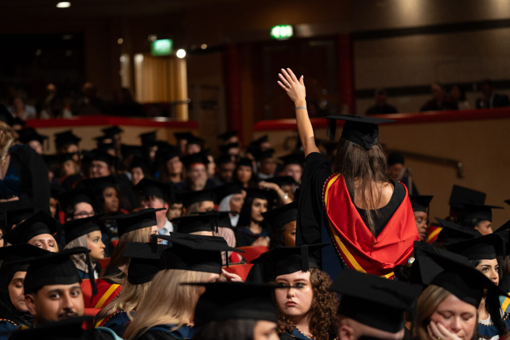 Student standing in the crowd waving