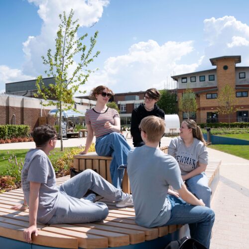 a group of people sitting on a round wooden bench outside